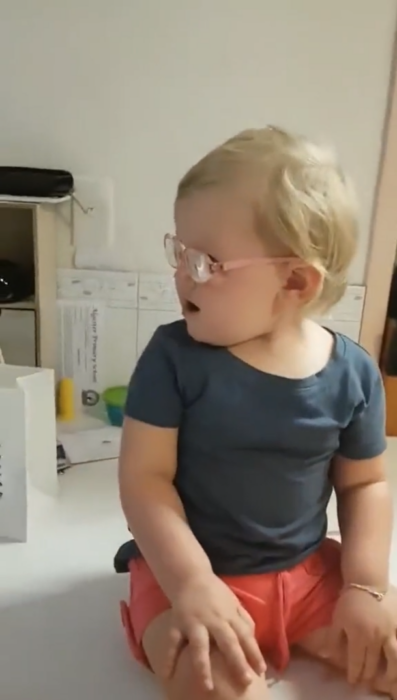 Sitting baby surprised by wearing glasses for the first time