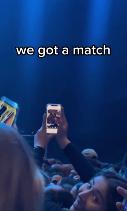 Mujer en concierto usando tinder en su celular