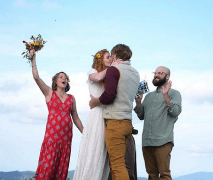 some bride and groom kiss after getting married they are accompanied by two people