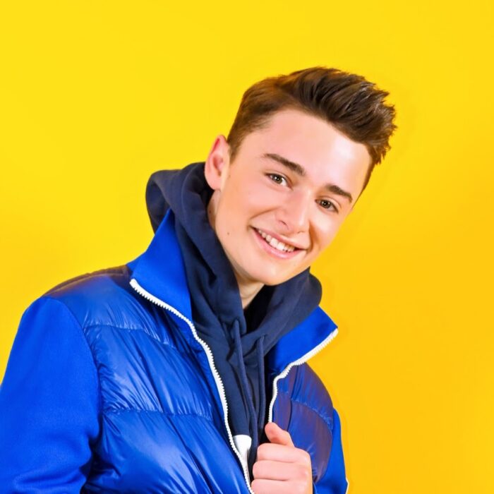 Noah Schnapp blue jacket yellow background