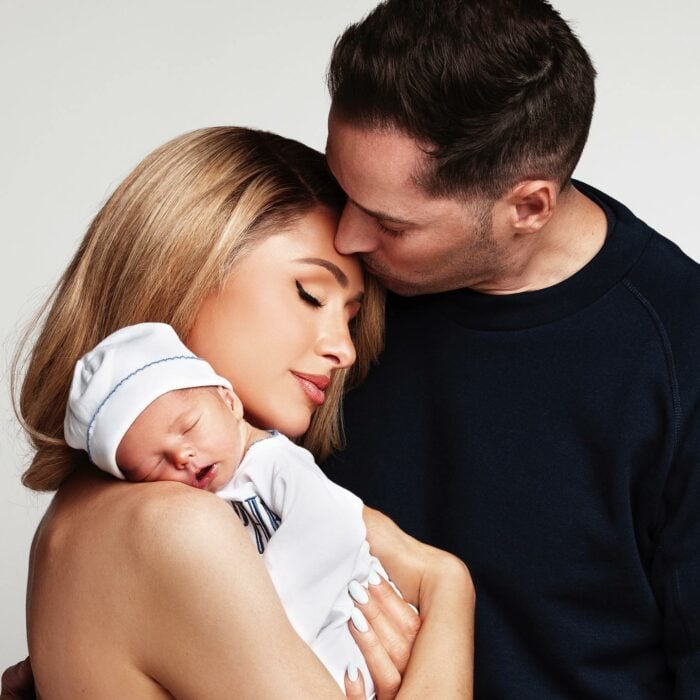 Paris Hilton cargando a su bebé junto a su esposo Carter Reum besándola en la frente 