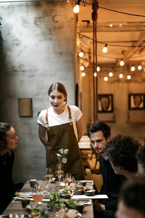 Comensales siendo atendidos por una mesera en un restaurante