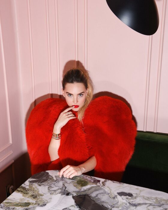 Fotografía de Belinda sentada en un restaurante usando un saco de peluche en color rojo 