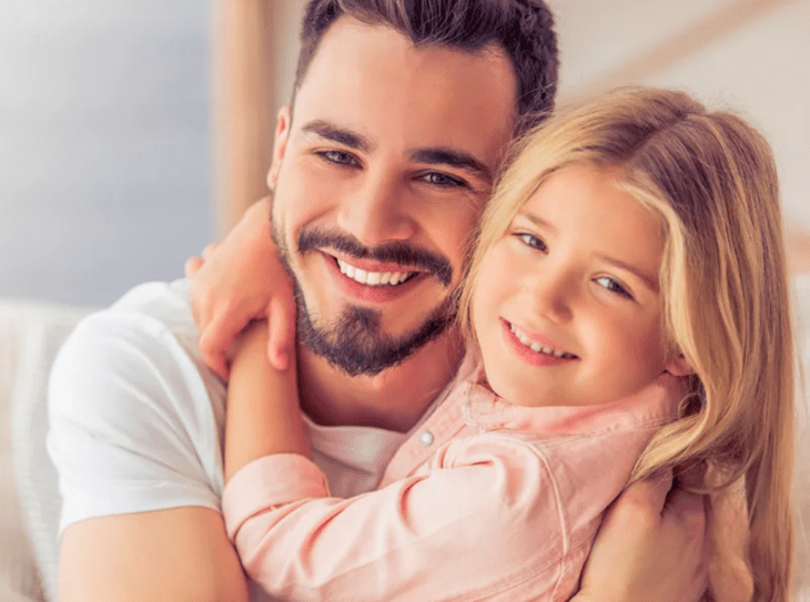 a little girl lovingly hugs her father they both smile 