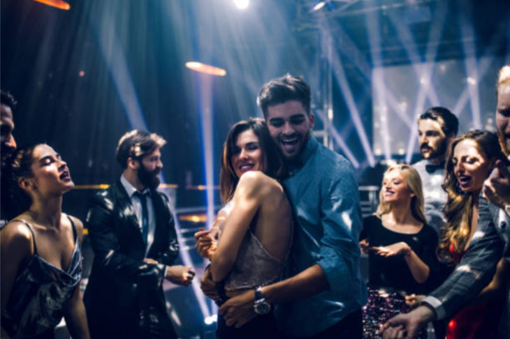 un grupo de personas bailan alrededor de una pareja en un antro 