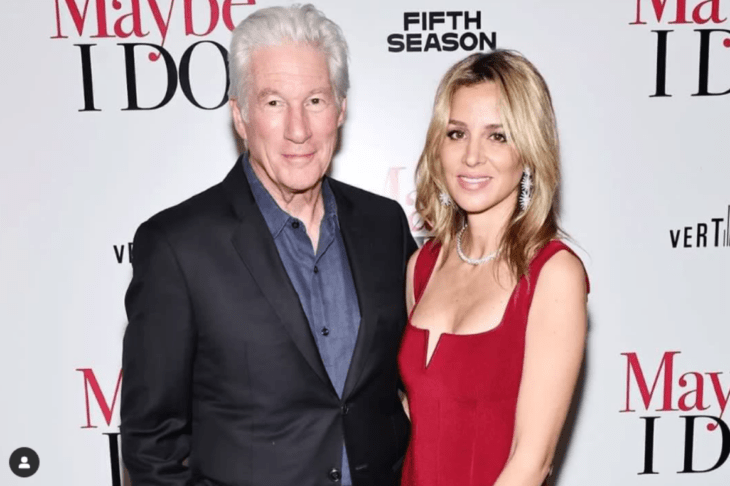 Image of Richard Gere and his wife Alejandra photographed on the red carpet of an event. She wears a red evening dress and he wears a suit with a dark shirt 
