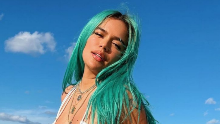 la cantante Carol G posando para la cámara en la playa lleva el cabello de color verde