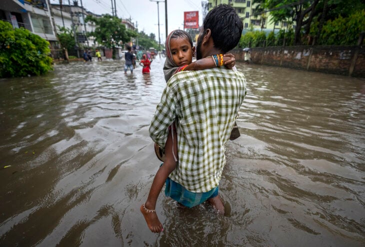 Hombre cargando a su hija en ciudad inundada