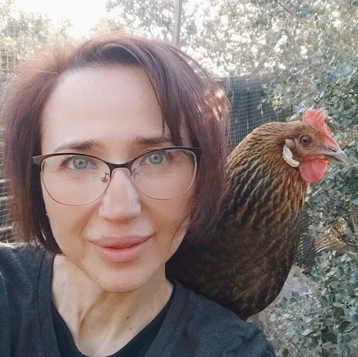 fotografía de una mujer con una gallina sobre su hombro derecho 