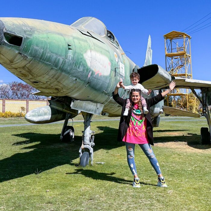 Mariana Echeverría cargando a su bebé frente a un avión 