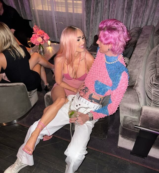 Megan Fox sentada junto a su prometido Machine Gun Kelly vestidos de color rosa en lo que parece ser una fiesta 