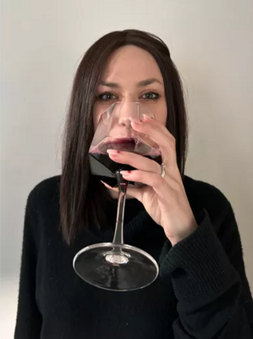 una chica bebiendo una copa de vino tinto