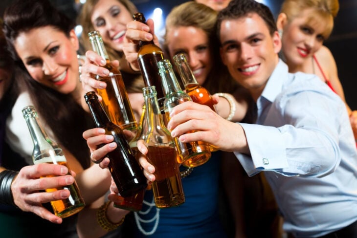 un grupo de amigos brindando con botellas de cervezas