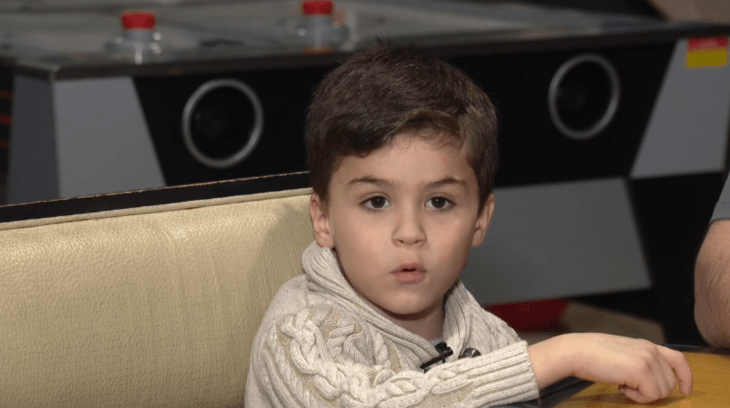 niño de seis años habla mientras está sentado en una silla