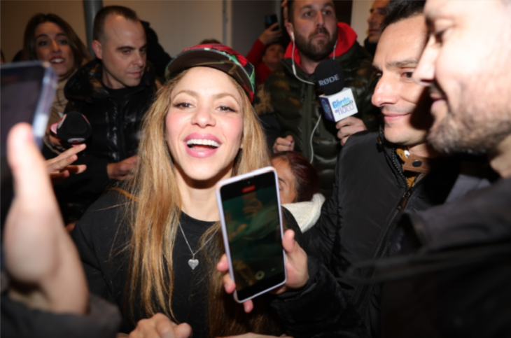 Shakira sonriendo rodeada de fanáticos y prensa