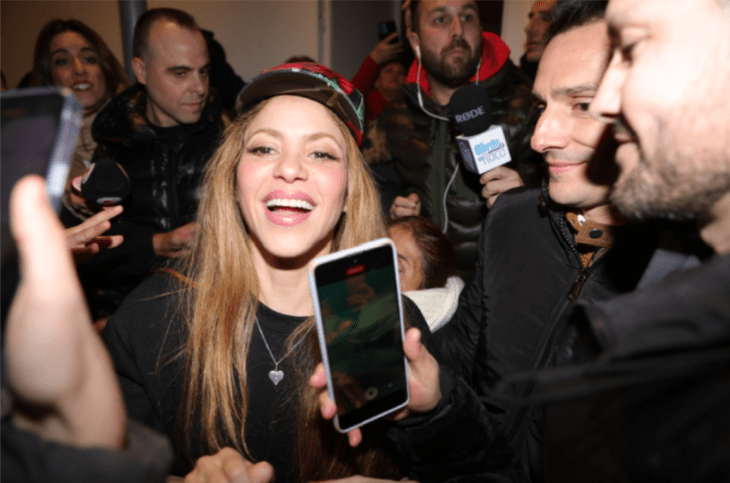 Shakira sonriendo rodeada de fanáticos y prensa