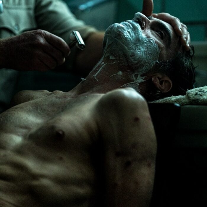 Joaquin Phoenix en su personaje de el guasón mientras le rasuran la barba en la película el Joker 
