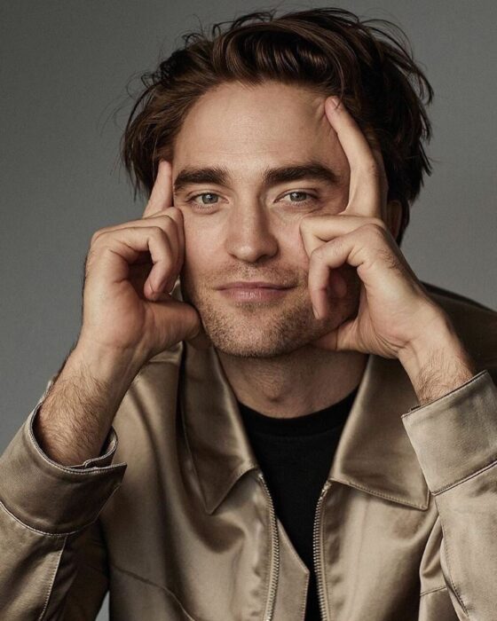 Robert Pattinson sentado con las manos en la cara