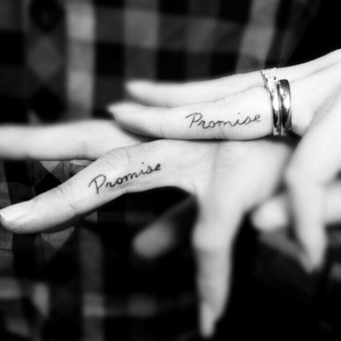 dedos de dos personas mostrando el mismo tatuaje con la palabra Promise 
