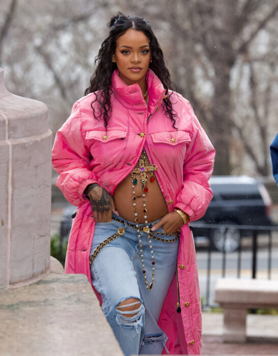 Rihanna posando embarazada con unos jeans a juego con un saco color rosa caminando por la calle 