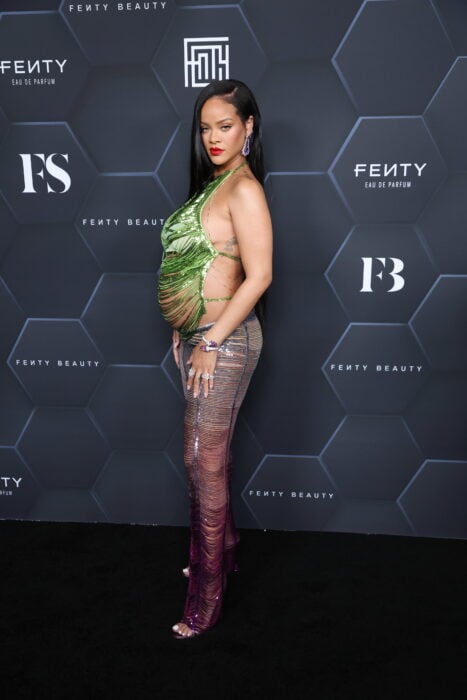 Rihanna posando en una alfombra roja con una blusa descubierta de los lados mostrando su pancita de embarazo 
