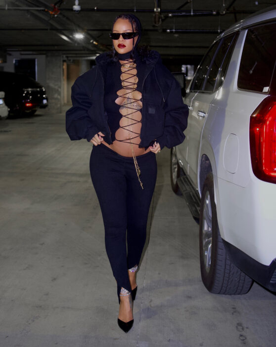 Rihanna posando con un atuendo sensual en color negro a lado de su camioneta 