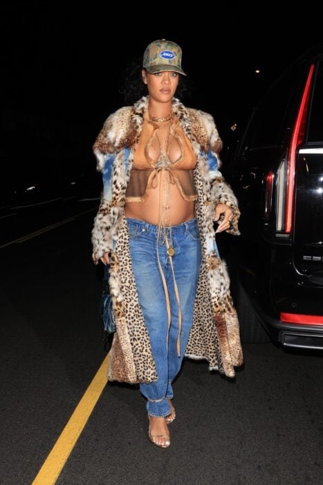 Rihanna mostrando su pancita de embarazo con una blusa larga de animal print a juego con unos jeans color azul 