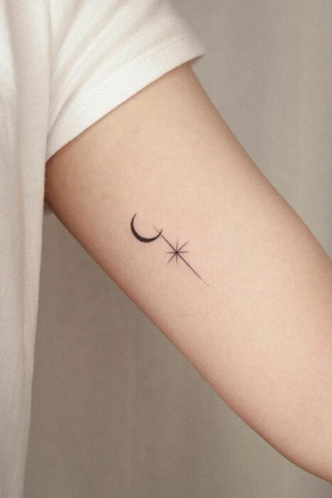 brazo de una chica mostrando un mini tatuaje de estrella con una luna 