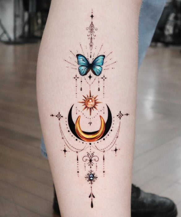 le bras d'une personne avec le dessin d'un tatouage avec des lunes et quelques détails de couleur 