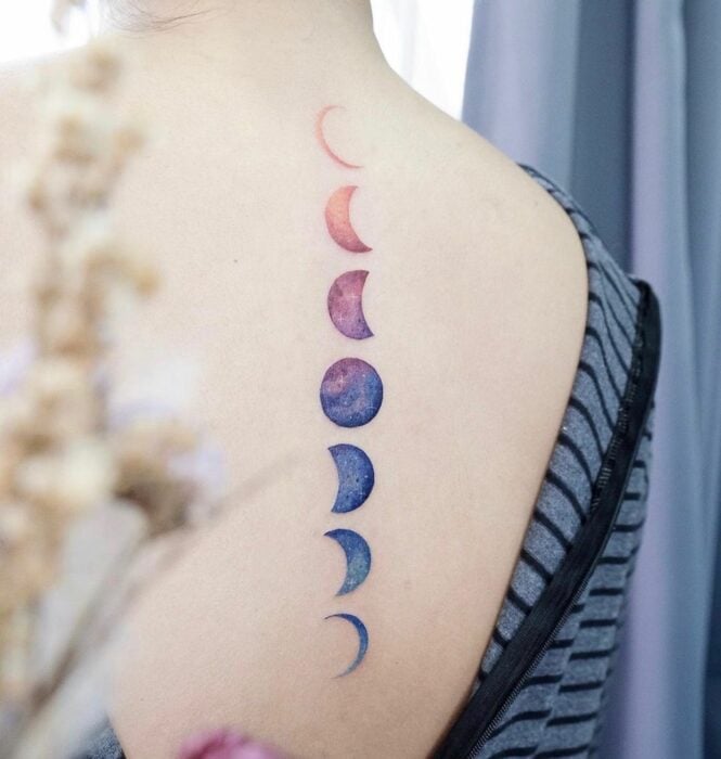 dos d'une fille montrant un tatouage avec les phases de la lune en bleu et rose 