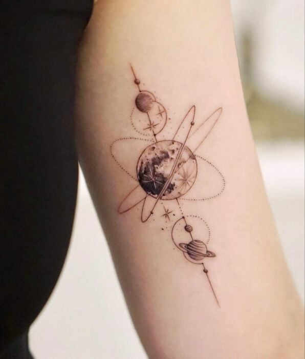 brazo de una persona mostrando un tatuaje de luna con algunos planetas 