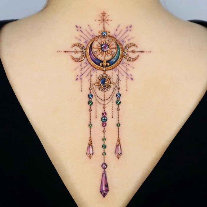 espalda de una mujer mostrando el diseño de tatuaje con cristales de colores al estilo de Sailor Moon 