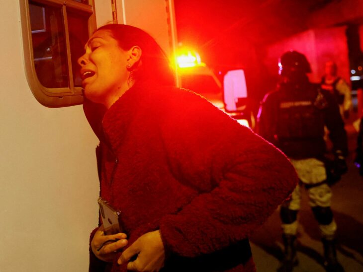 Mujer migrante llorando afuera de una ambulancia tras incendio en centro de detención en Ciudad 