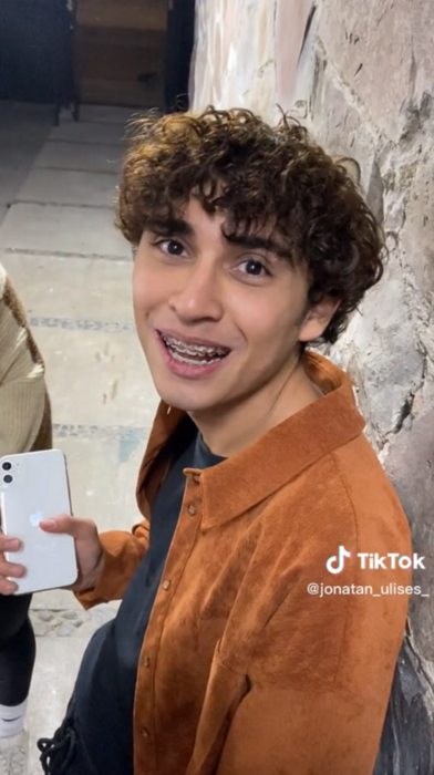 imagen de un chico que voltea a la cámara sonriente mientras sostiene su celular