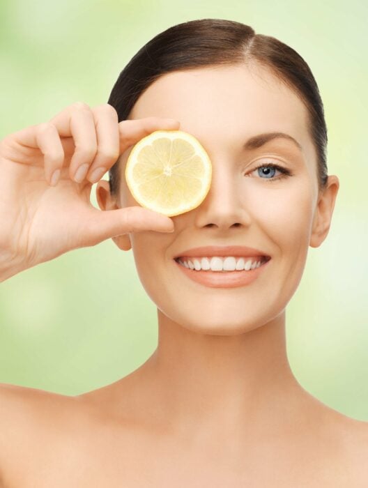 Imagen de una mujer con una rodaja de limón sobre su ojo izquierdo 