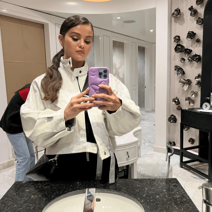 Selena Gomez con su celular frente al espejo tomándose una selfi 