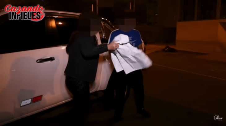 a couple argues in a dark street she tears some sheets that she carries in her hands