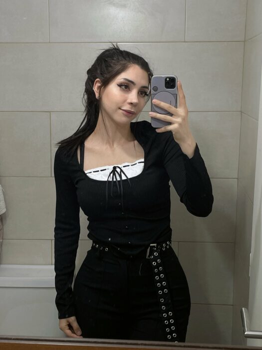 Photograph of a girl dressed in black posing in front of her bathroom mirror 