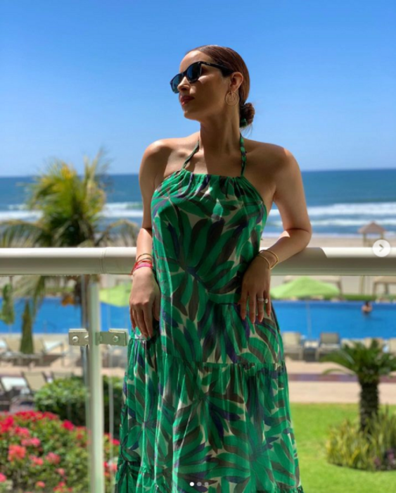 Cynthia Rodríguez posa en un balcón mientras está en la playa lleva un vestido largo suelto