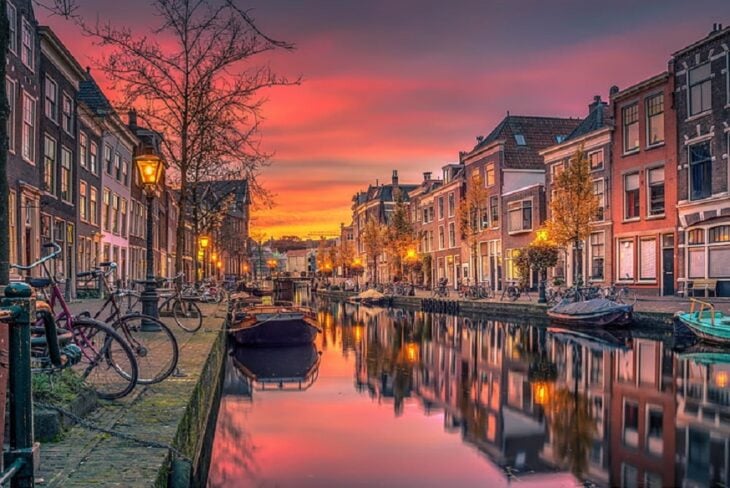 una imagen de un canal de agua que corre en una de las calles de los Países bajos está amaneciendo