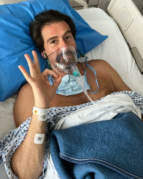 Fotografía de Eduardo Videgaray acostado en una cama de hospital con una mascarilla de nebulizaciones en el rostro 