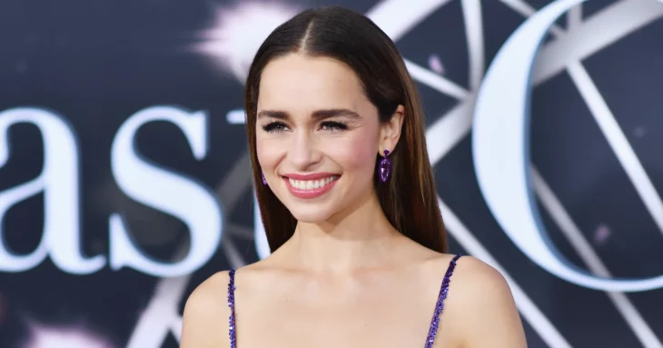 Emilia Clarke sonrie en la alfombra roja de un evento en Hollywood lleva un vestido de tirantes delgados