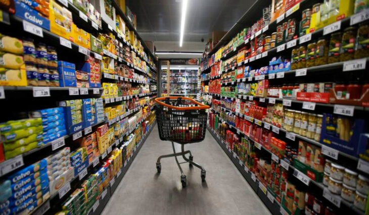 imagen de los estantes de un supermercado con un carrito en el pasillo