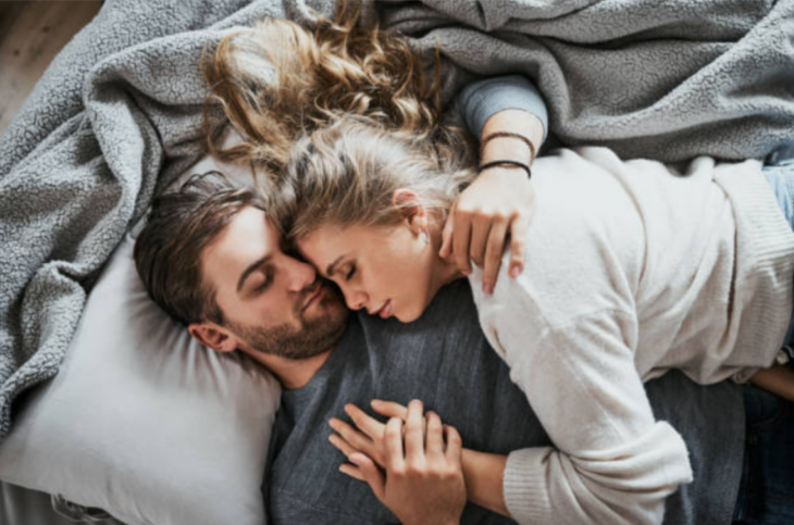 una joven pareja están acostados durmiendo juntos llevan ropa cómoda y se toman las manos