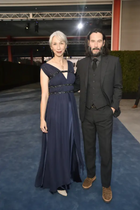 Keanu Reeves y Alexandra Grant de pie sobre la alfombra en algún evento de Hollywood