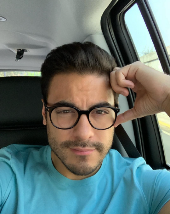 Carlos rivera con lentes transparentes está sentado en su auto mientras mira a la cámara