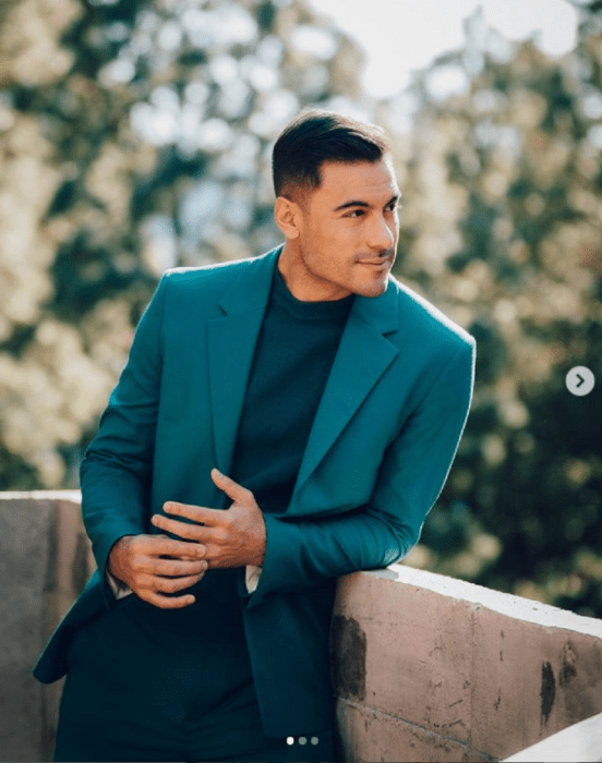 Carlos Rivera looking at the horizon wearing a green jacket is standing on a balcony