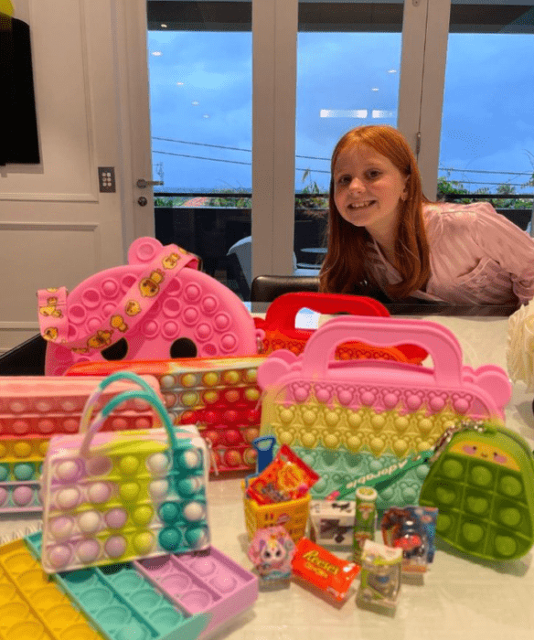 una chica posa junto a varias bolsas de colores de una colección para niñas 