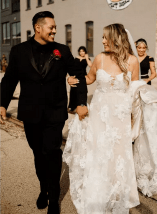 a wedding couple walks through the room where their reception is taking place, they are arm in arm