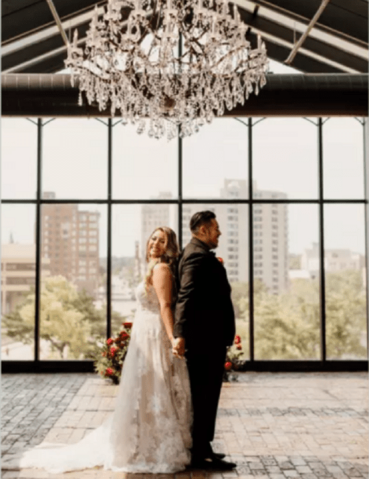 couple holding hands back to back in a room with huge stained glass windows